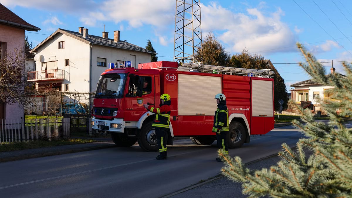 Two firefighters stand near a firetruck on a quiet suburban street, showcasing readiness and safety.